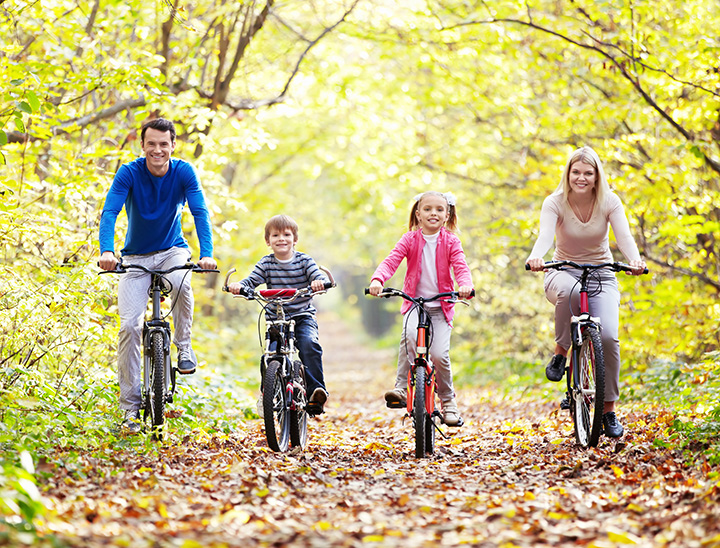 Image of family cycling along a cycle path in a green, leafy setting